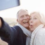 Senior Couple enjoying a long happy life Standing On Beach Taking Selfie