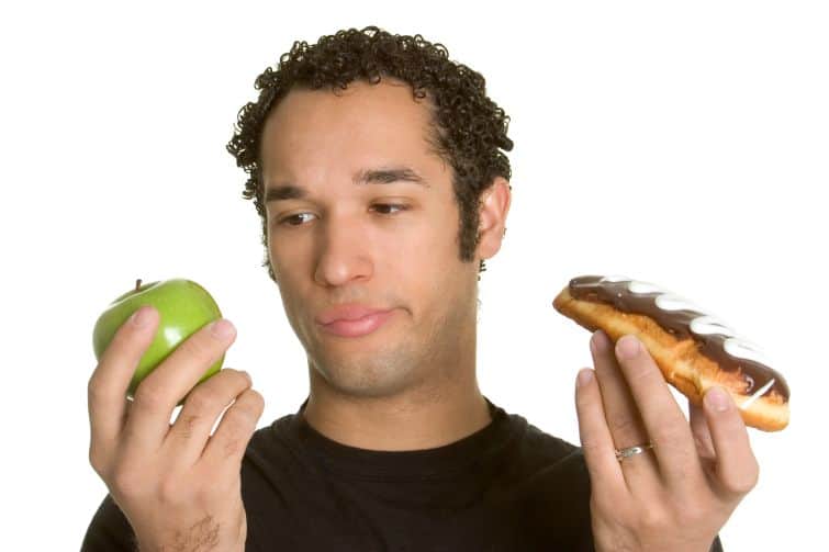 Man holding an apple and a donut having to choose in order to achieve smarter goals